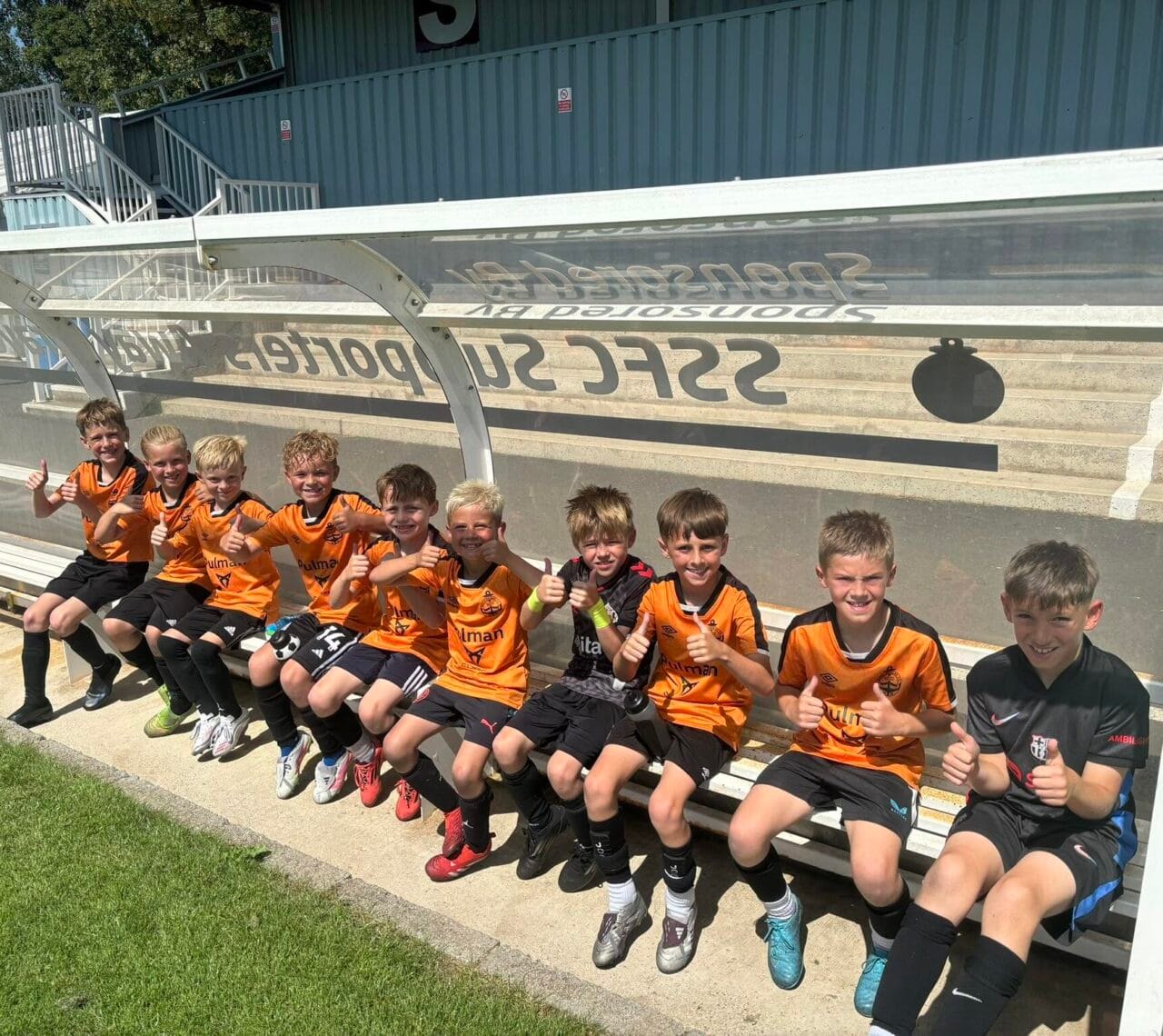 Young Academy players sat in shelter on SSFC grounds, smiling at the camera.