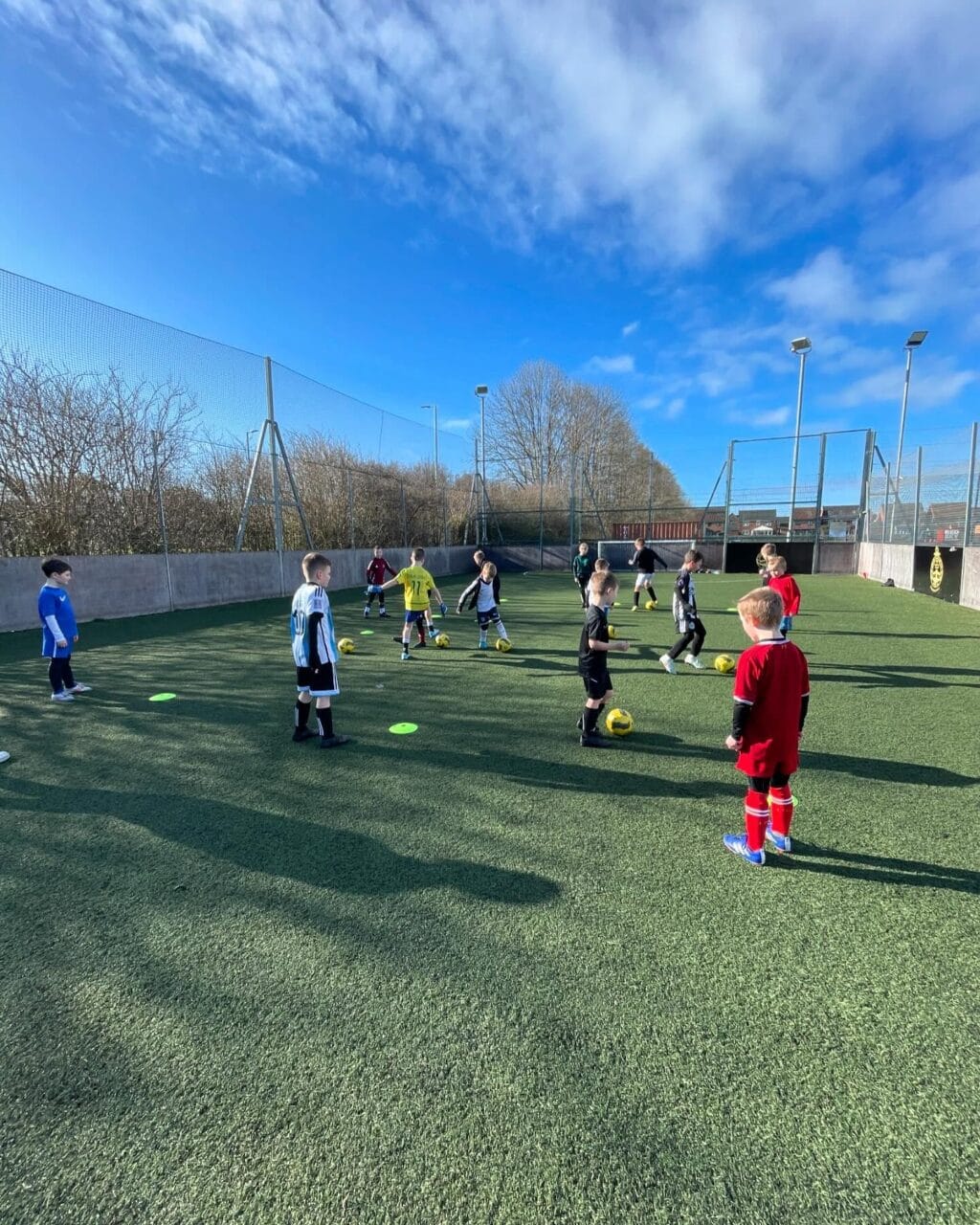 Young children playing football in fenced pitch at South Shields FC Foundation.